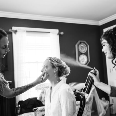 Bride getting makeup done hairspray spraying
