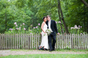 bride and groom in park by fence and flowers