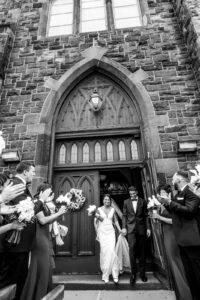 Bride and groom black and white coming out of church doors