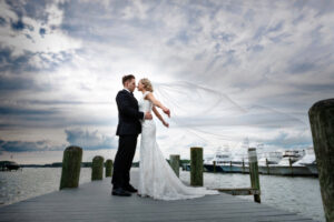 Bride with long vail blowing in wind on dock