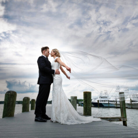 Bride with long vail blowing in wind on dock