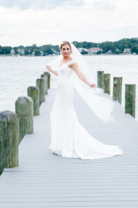 Bride with long vail blowing in wind on dock