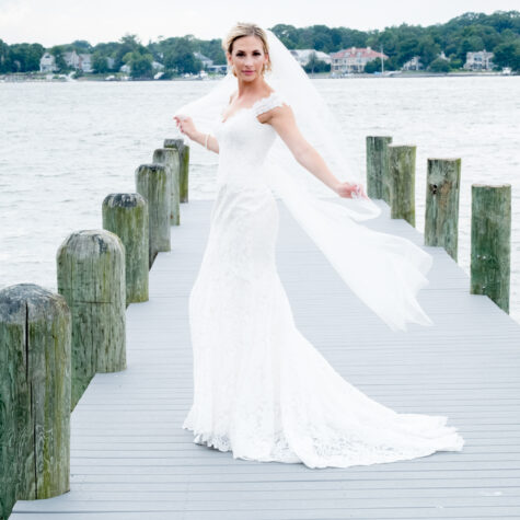 Bride with long vail blowing in wind on dock