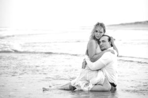 Fun sexy couple in water on beach in clothes