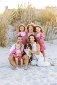 Family with dog sitting on beach dunes