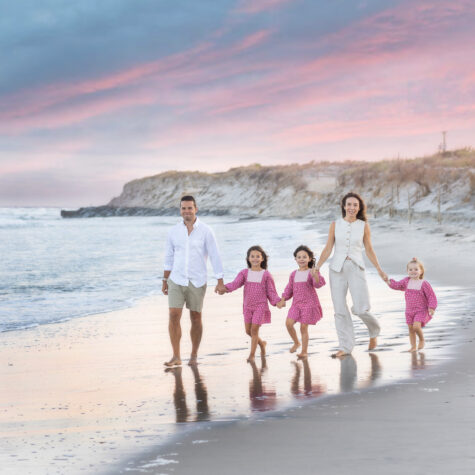 family walking on beach at sunset