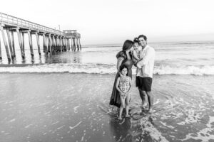 black and white family on beach by pier natural candid moment
