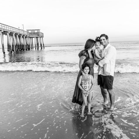 black and white family on beach by pier