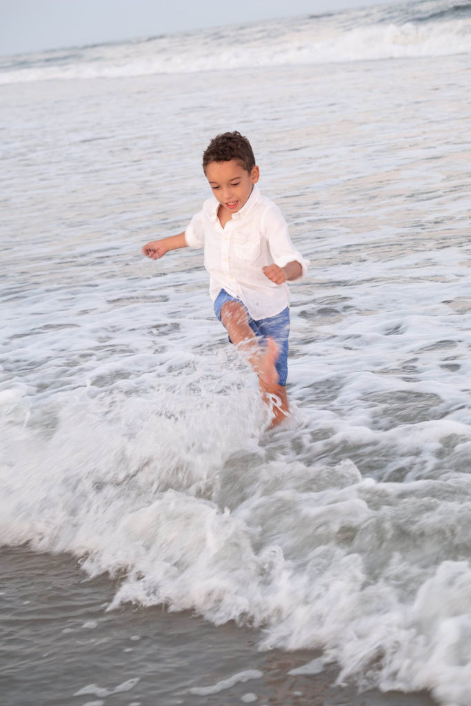 little boy playing in ocean portrait