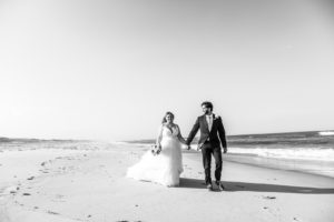 bride and groom walking ocean beach
