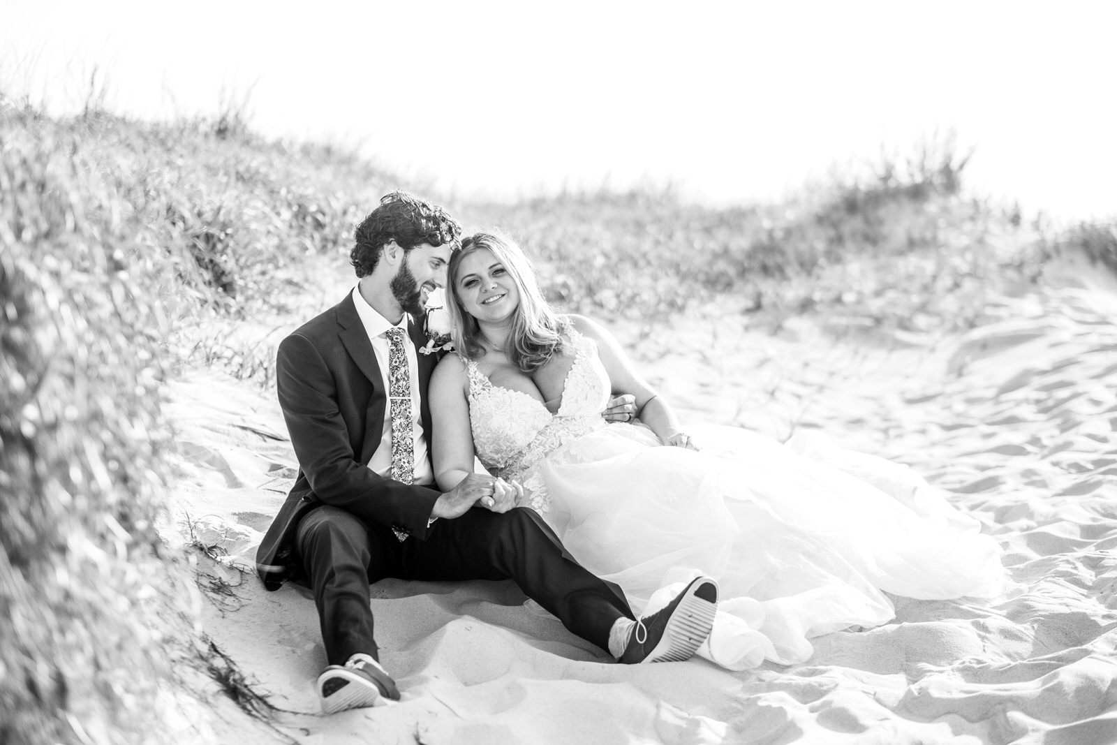 black and white bride and groom beach sitting