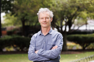 Man headshot outdoors green trees background