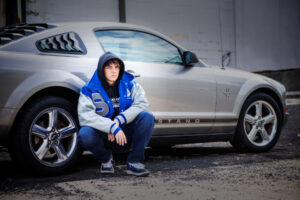 H.S. Senior boy by car in varsity jacket