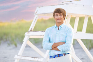 High school senior boy on beach by lifeguard stand