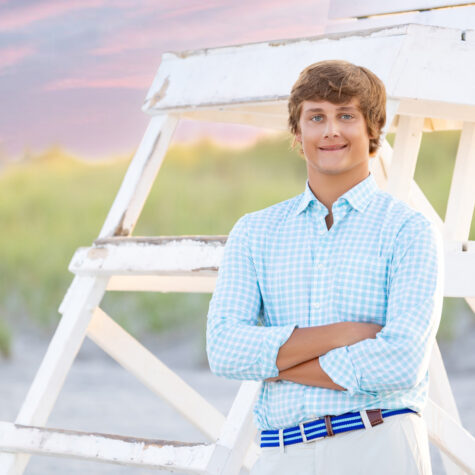 High school senior boy on beach by lifeguard stand