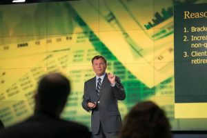 Business man speaking in front of screen on stage
