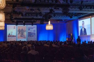 Large corporate conference ballroom stage speaker at podium