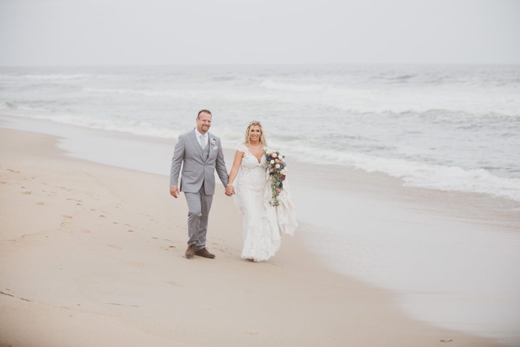 Bride and groom holding hands walking beach