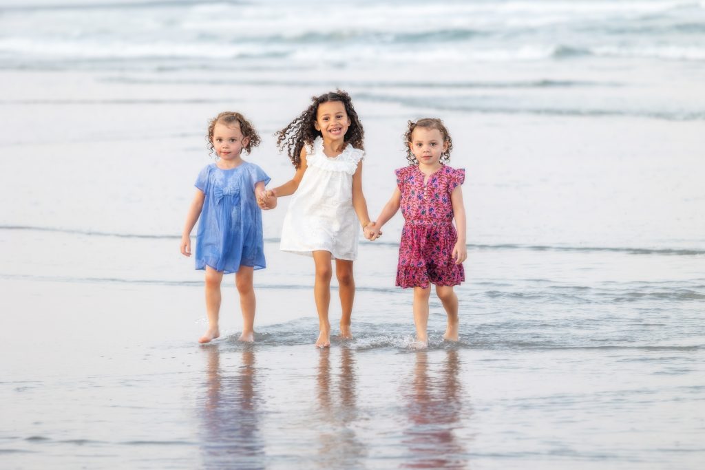 Little girls holding hands walking beach