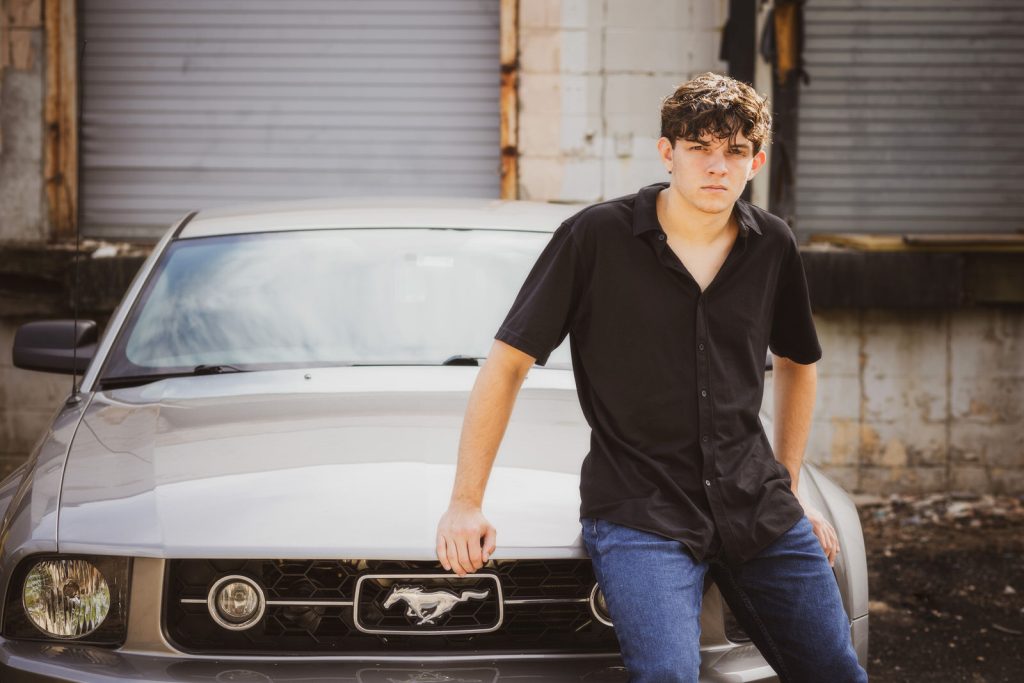 senior boy sitting on car