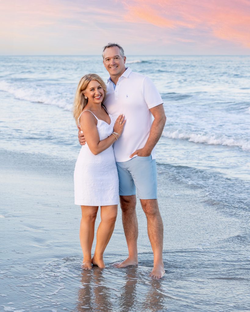 Couple standing at ocean at sunset