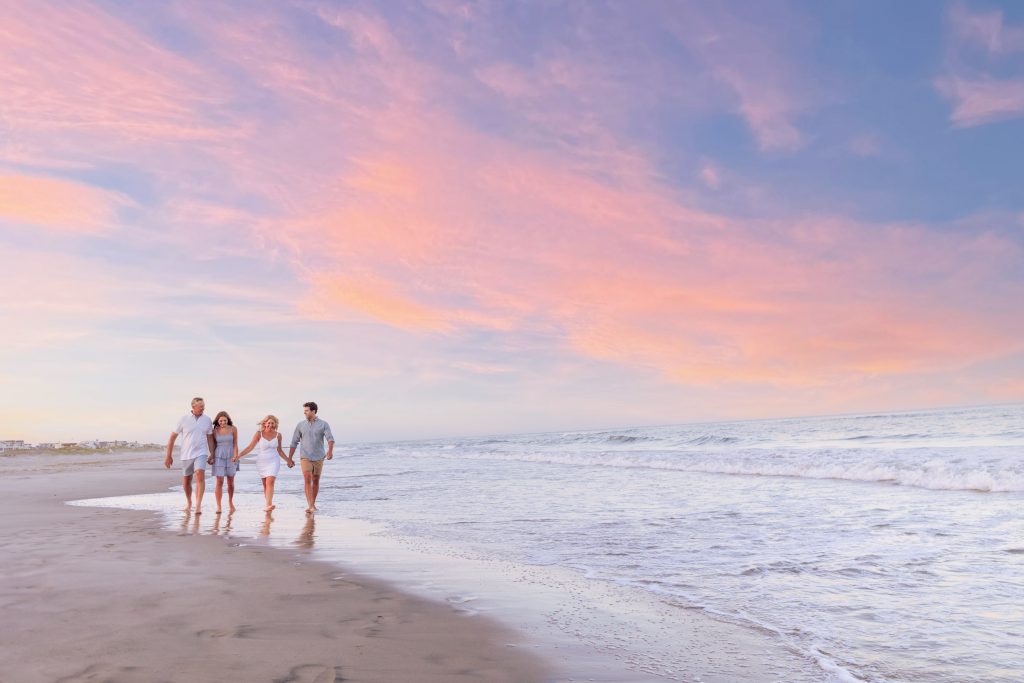 Family walking on beach at sunset