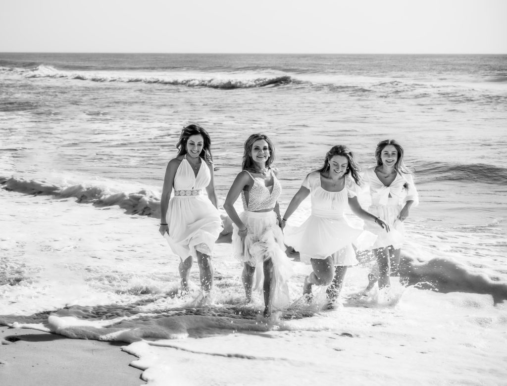 Black and white girls in dresses running in ocean