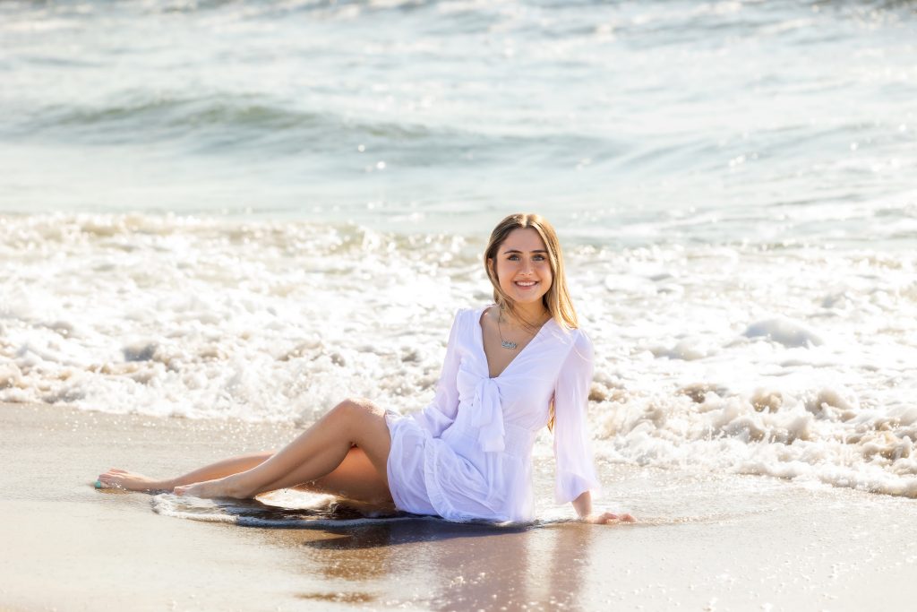 Girl sitting in ocean wearing dress 