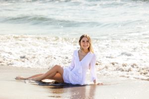 Girl sitting in ocean wearing dress