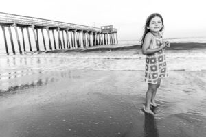 Black and White little girl on beach by pier