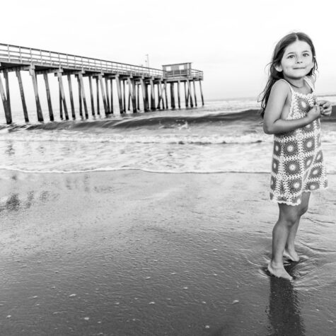 Black and White little girl on beach by pier