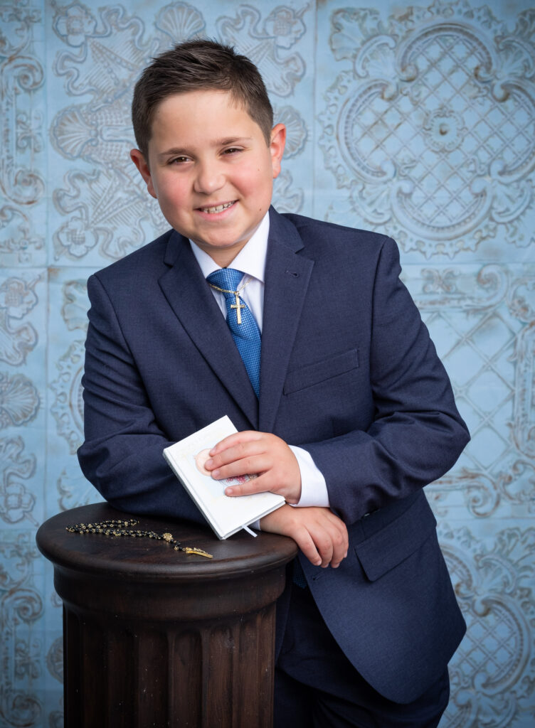 Boy wearing suit holding bible and rosary communion portrait