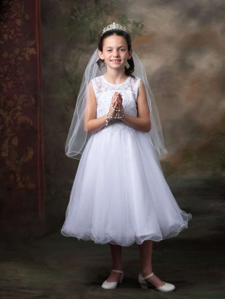 Girl in white communion dress praying rosary