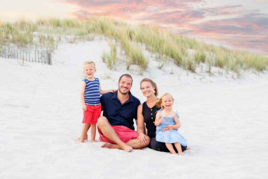 family sitting on beach at sunset