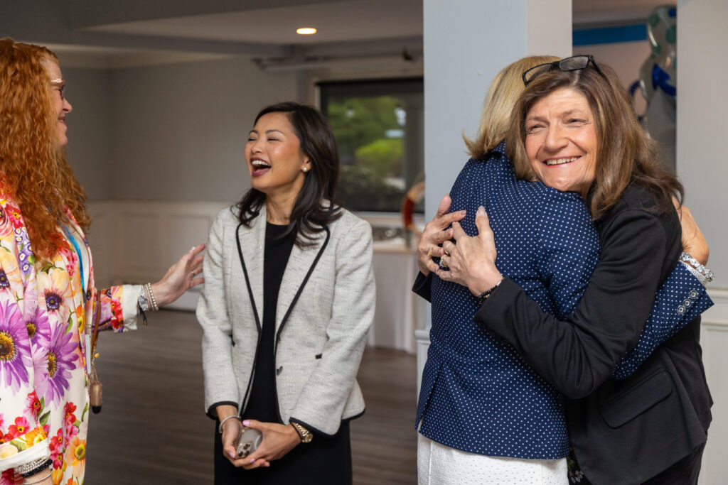 Women laughing and hugging at business event