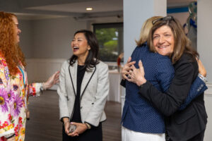 Women laughing and hugging at business event